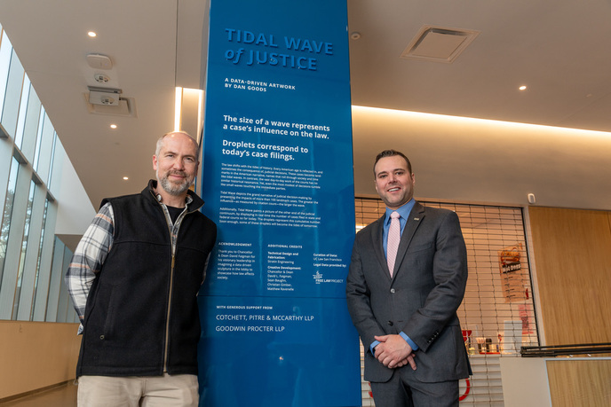 Artist Dan Goods and Christopher Gabriel of Stratin Engineering standing next to the Tidal Wave of Justice informational display.